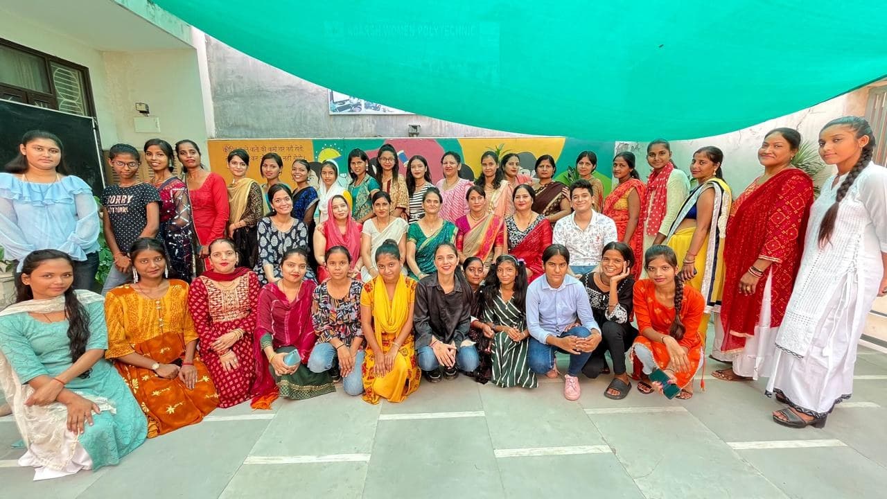 A large assembly of students and faculty at Adarsh Women’s Polytechnic, seated together in a hall.