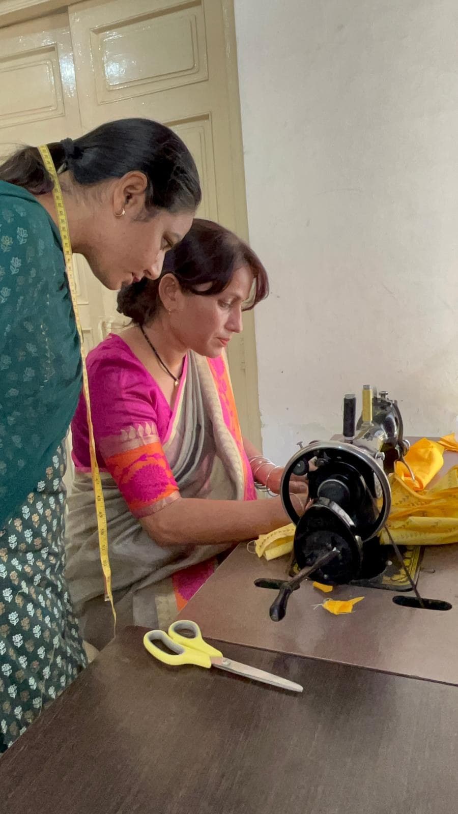 An instructor teaching a student at a sewing machine at Adarsh Women’s Polytechnic.