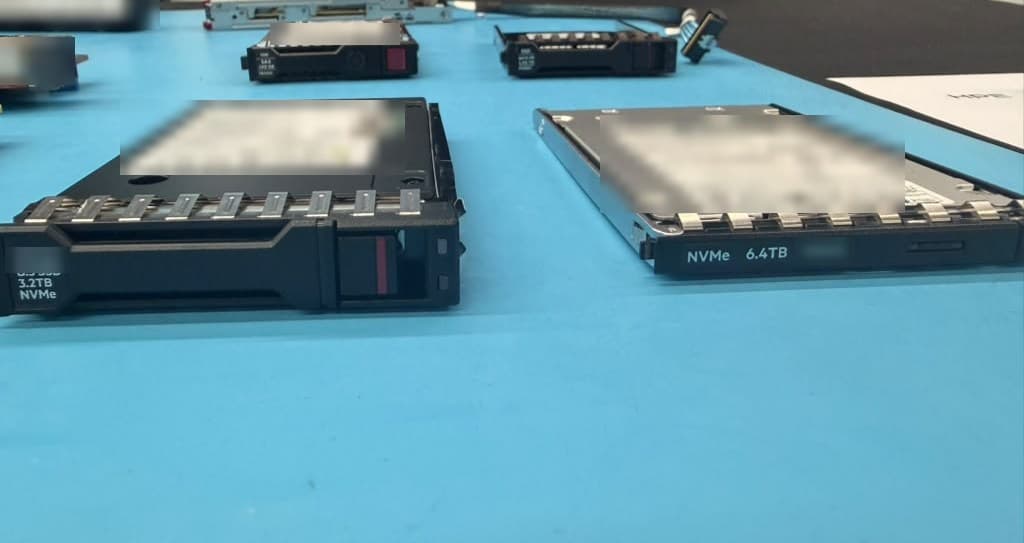 NVMe solid-state drives in hot-plug carriers on a table, one marked 3.2TB and one 6.4TB.